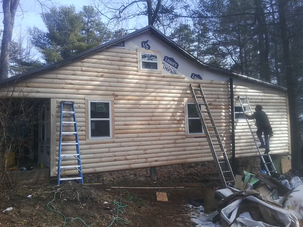Ladders set against fresh log siding during an exterior remodel in Grafton